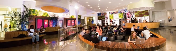 Wide view inside the Full Sail Entertainment Business building, with plants and Hall of Fame memorabilia around.